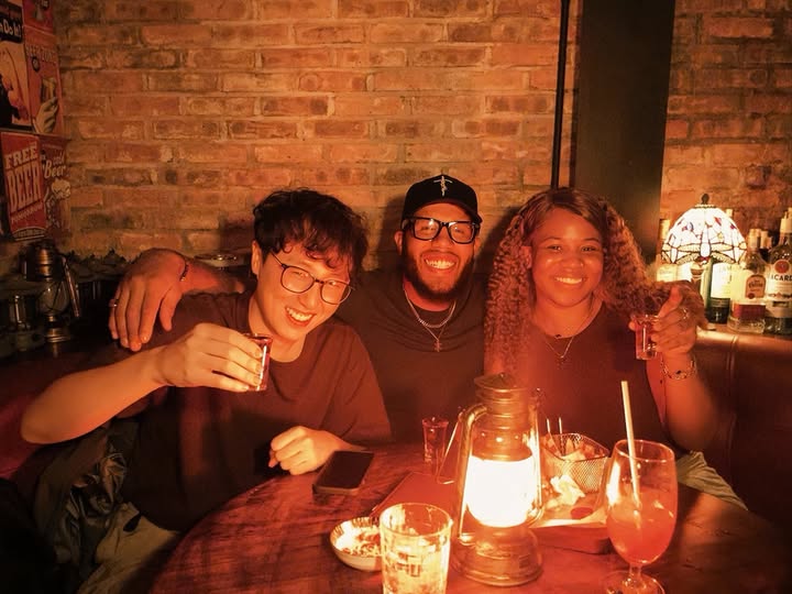 Three friends smiling together over drinks at Cheers